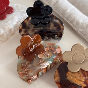 Close-up of four floral acetate hair claws with Barrette la France gold lettering detail