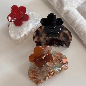 Detailed macro view of acetate flower hair claws in pearl white, tortoiseshell, and marble