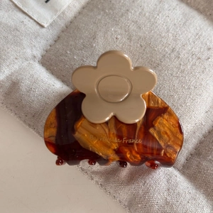 Close-up of tortoise shell hair claw clip with beige flower and Barrette la France text