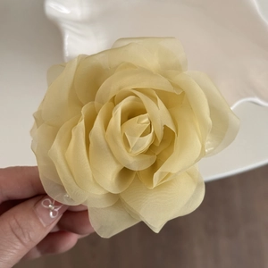 Close-up of lightweight champagne organza rose hair claw with delicate layered petals