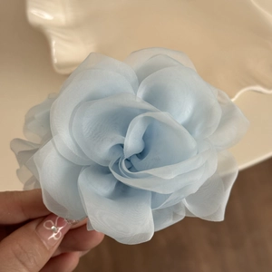 Detail of a light blue organza rose hair claw clip with delicate translucent petals