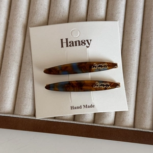 Detail of tortoise shell acetate hair clips with gold logo on a jewelry display tray