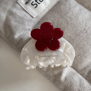 Detailed macro of medium acetate hair claw with white marble texture and red flower