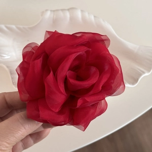 Macro detail of high-end deep red gauze rose hair clip on a white shell plate