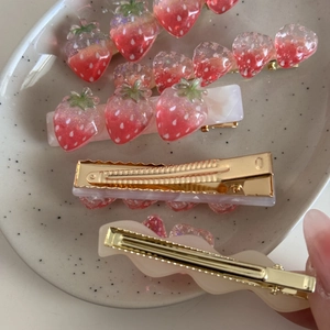 Dettaglio di fermagli per capelli a fragola in resina rosa con clip a becco d'oro