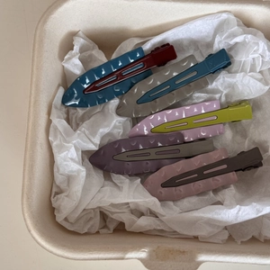 Lot de cinq pinces à cheveux métalliques ondulées aux couleurs contrastées sur papier