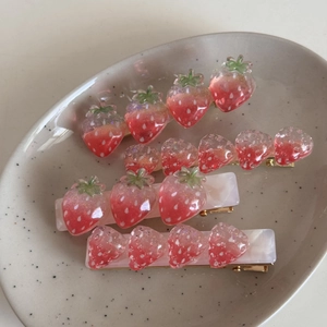 Detailopname van de hars aardbei haarklemmen met glitter op een keramische schaal