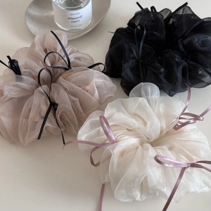 Detailed close-up of three organza bow scrunchies in champagne, black, and off-white