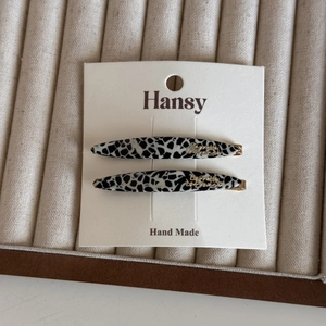 Detail view of two French style acetate hair clips with leopard print and gold accents