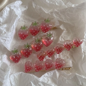 Detailopname van aardbei haarspelden van hars met een goudkleurige metalen basis