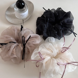 Close-up of sheer organza scrunchies in black, beige, and cream with ribbon bows