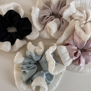 Pleated satin scrunchies set in champagne, black, and blue with ruffled edge details