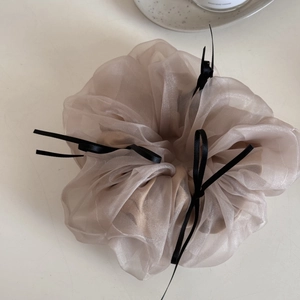 Close-up detail of champagne organza hair scrunchie with black silk ribbon bows