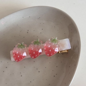 Dettaglio del fermaglio per capelli alla fragola con base in resina marmorizzata e bacche