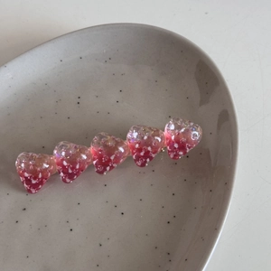 Dettaglio del fermaglio per capelli a fragola in resina rosa con finitura glitter