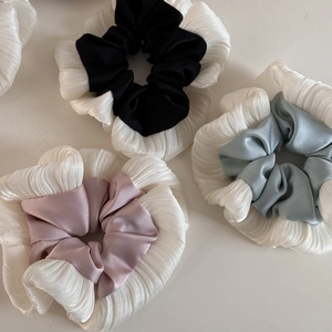 Detailed macro view of soft pleated fabric and satin textures on elegant hair scrunchies