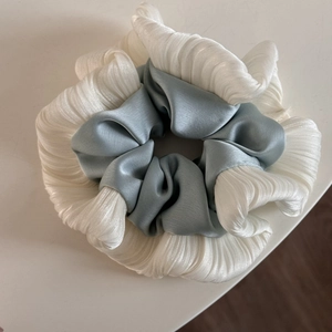 Detail of two-tone scrunchie showing white pleated fabric and grey-blue satin texture