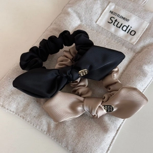 Close-up of black and champagne satin bow hair ties with engraved metal charms