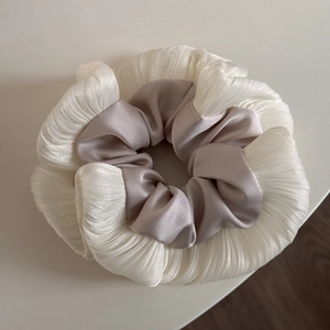 Close-up of pleated white fabric and lavender satin texture on scrunchie
