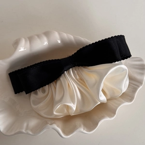 Detail of French vintage black bow hair clip with cream satin pleats on a shell tray