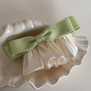 Detail of light green ribbon bow hair clip with creamy satin pleated ruffle design