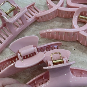 Close-up of assorted pink hair claw clips in various shapes on a marble surface