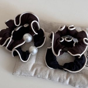Detailed view of elegant hair scrunchies with white pearl accents and contrast borders