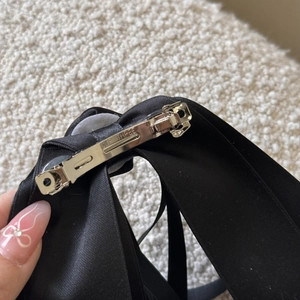Detail view of the metal spring clip on a black satin ribbon hair bow for women