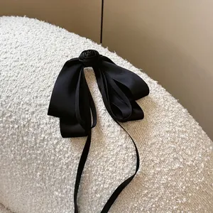 Elegant black satin bow hair clip featuring a handmade rose center and long silk ribbons