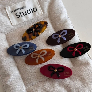 Set of six colorful acetate bow hair clips with crystal accents on a canvas background