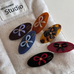 Close-up of handmade oval hair clips with sparkling crystal bows in six vintage colors