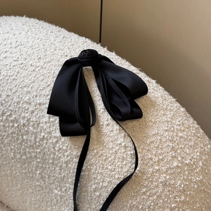 Detail shot of black satin bow hair clip with rose accent and long elegant streamers