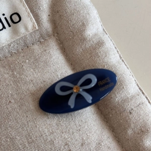 Detailed close-up of handmade blue acetate hair clip with bow and France label