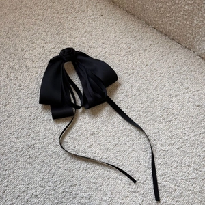 Close-up of elegant black satin ribbon bow hair clip with a delicate handmade rose flower
