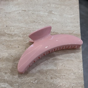 Detailed close-up of light pink resin hair claw clip on marble background