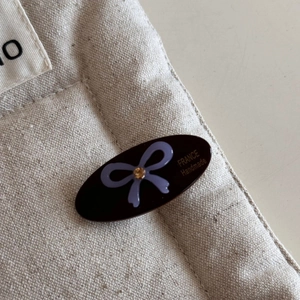 Detailed macro view of an oval black resin hair clip with purple bow and sparkling crystal
