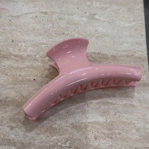Detailed top view of a glossy pink large hair claw clip on a marble surface
