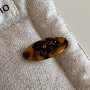 Detail of tortoise shell acetate hair clip with black bow and amber rhinestone on canvas
