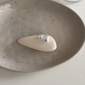 Detalle de pinza para el pelo crema con perlas sobre un plato de cerámica