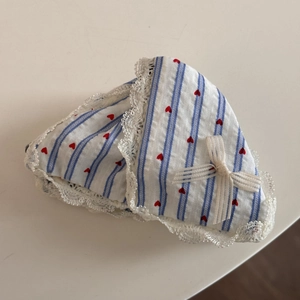 Dettaglio dell'elastico a righe con cuori rossi e bordo in pizzo bianco fine
