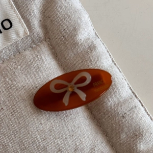Close-up of amber acrylic bow hair clip featuring France Handmade engraved text