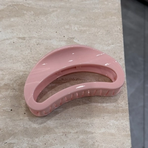 Detail view of pink geometric hair claw clip on marble background for back of head styling