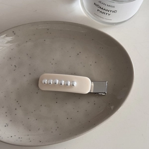 Primer plano detallado de una pinza para el pelo de estilo francés con perlas blancas