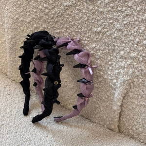 Detail showing rhinestone bows and silk pleats on black and lavender headbands