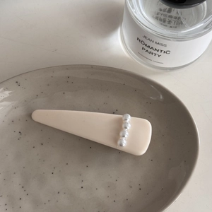 Detalle de pinza para el cabello mate crema con cuatro perlas elegantes en cerámica