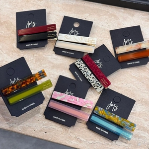 Elegant acetate baguette hair clips with golden logo on a stylish marble background