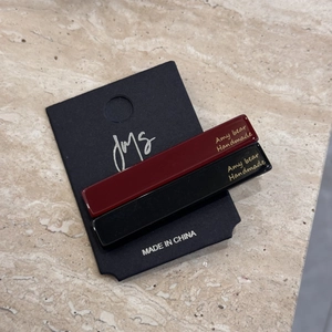 Detail view of burgundy and black rectangular hair clips on a JmS display card