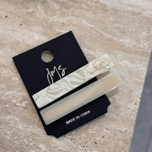 Detail view of marble pattern and beige acetate hair clips on a premium display card