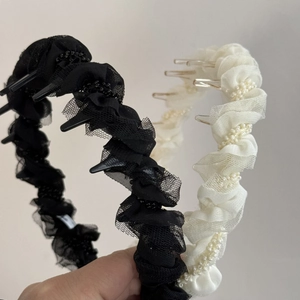 Détail de deux serre-têtes en tulle plissé noir et crème ornés de petites perles fines