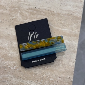 Detail of two handmade acetate hair clips with marble patterns on a black display card